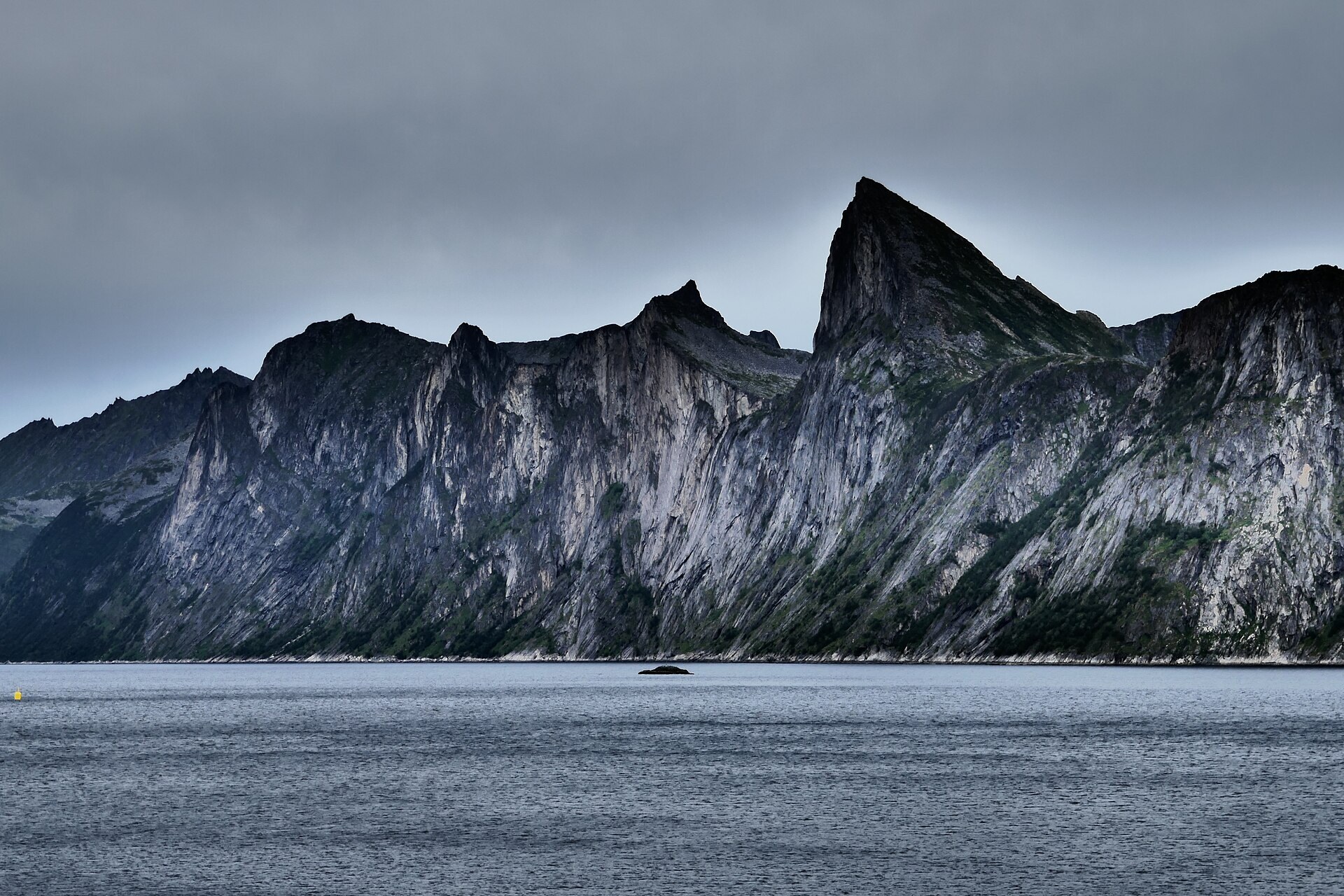 A dark rock wall plunging into Mefjord